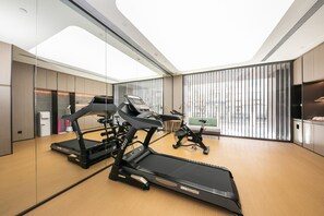 A modern gym with treadmills, stationary bikes, and a mirrored wall. - Ji Hotel (Beijing)