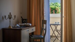 A room with a desk, chair, and a view of a balcony with outdoor furniture and plants. - Hotel Boutique Natka (Rovinj)