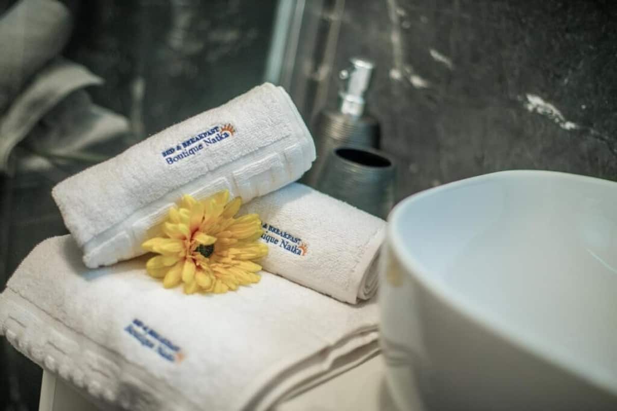 A bathroom with a white towel, a yellow flower, and a bottle of lotion on a counter.