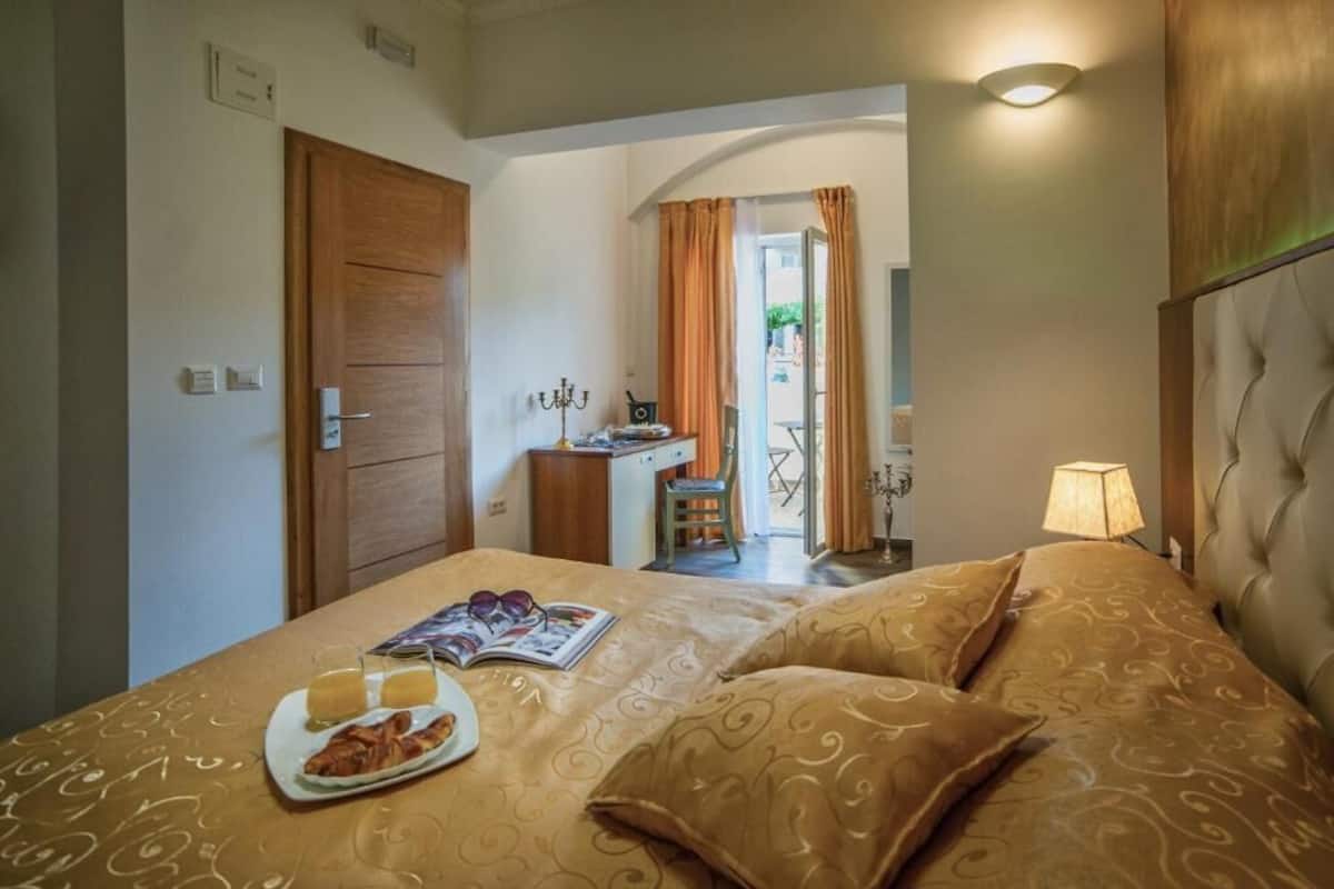 A hotel room with a bed, a desk, a chair, and a lamp.