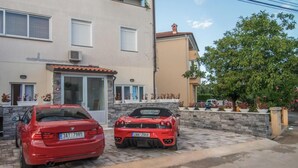 Two red cars parked in front of a building with a stone facade and a tiled roof. - Hotel Boutique Natka (Rovinj)