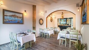 A dining area with multiple tables and chairs, a large painting on the wall, and a mirror above the tables. - Hotel Boutique Natka (Rovinj)