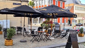 Outdoor seating with black umbrellas, a sign for 'The Witch', and a brick building in the background.