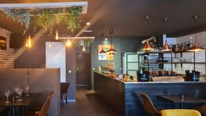 A modern bar area with brick walls, hanging light bulbs, and a bar counter with bottles and glasses.