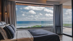 A modern bedroom with a large window offering a view of the ocean and sky. - Ocean View Casa Nina, Santa Teresa - 2 Bedrooms! (Santa Teresa)