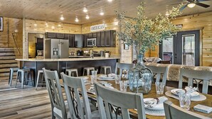 A wooden cabin interior with a kitchen, dining area, and a sign labeled "AMERICAN." - Mountain Chalet in Gatlinburg with Indoor Pool, Game Room, Hot Tub & 3 Decks! (Gatlinburg)