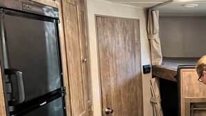 A compact kitchen with wooden cabinets, a black refrigerator, and a small countertop. - New updated, larger 1BR trailer, minutes from WEC and HITS, peaceful setting;  (Morriston)