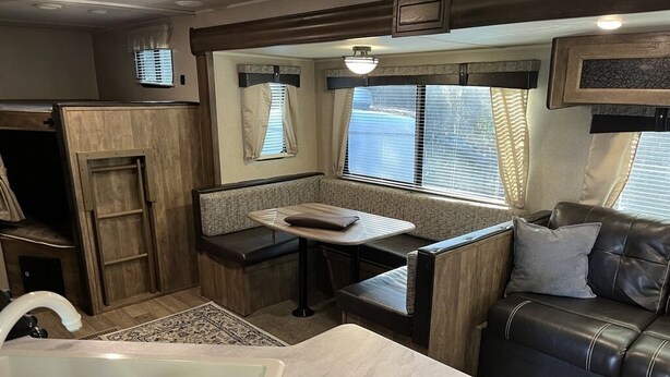 A compact RV interior with a kitchenette, a dining area, and a seating area with a couch and a table. - New updated, larger 1BR trailer, minutes from WEC and HITS, peaceful setting;  (Morriston)