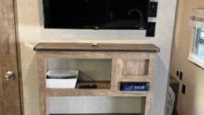 A room with a built-in TV on a wooden cabinet, a door, and a window with blinds. - New updated, larger 1BR trailer, minutes from WEC and HITS, peaceful setting;  (Morriston)