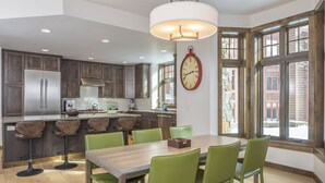 Una cocina moderna con una isla grande, sillas verdes y una mesa de comedor.