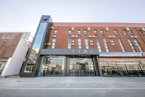 Un hotel con fachada moderna, amplio acceso de vidrio y varios equipos de aire acondicionado.