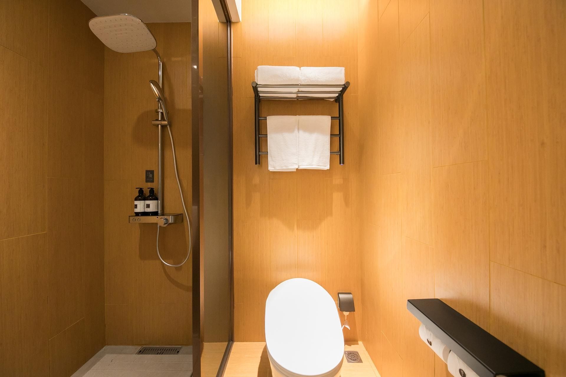 Un baño con ducha, inodoro y perchero para toallas.