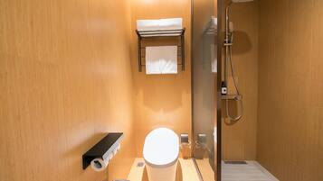 A compact bathroom with a toilet, a towel rack, a shower, and a waste bin.
