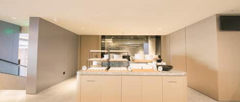 A modern kitchen with a marble countertop, built-in appliances, and a flat-screen TV mounted on the wall.