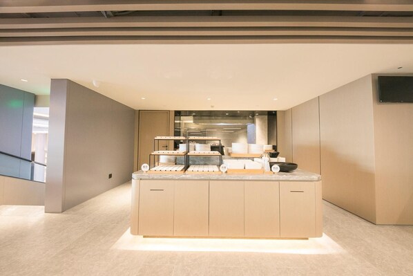 A modern kitchen with a marble countertop, built-in appliances, and a flat-screen TV mounted on the wall. - Ji Hotel Beijing Happy Valley (Beijing)