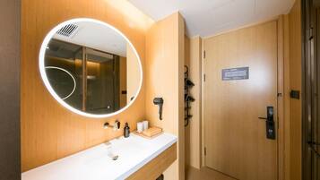 A modern bathroom with a round mirror, a white sink, and a wooden vanity.