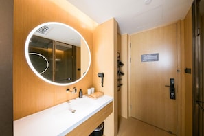 A modern bathroom with a round mirror, a white sink, and a wooden vanity. - Ji Hotel Beijing Happy Valley (Beijing)