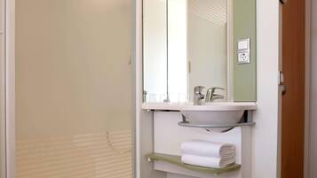 A bathroom with a shower, a sink, a mirror, and a towel rack.