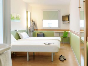 A hotel room with two beds, a desk, a chair, a TV, and a suitcase. - Ibis Budget Lleida (Lleida)