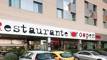 A building with a sign reading 'Restaurante Open' and a car parked in front.