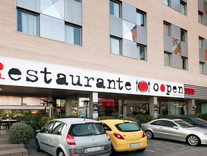 A building with a sign reading 'Restaurante Open' and a car parked in front. - Ibis Budget Lleida (Lleida)