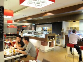 Un restaurante con mostrador, mesas y sillas.