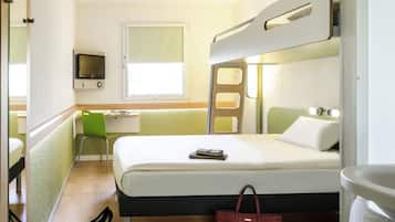 Habitación de hotel compacta con literas, un escritorio con silla, televisor y ventana.