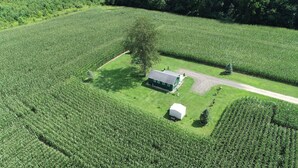 Vue aérienne d’une ferme avec une serre, une grange et un chemin de terre.