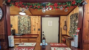 Un intérieur en bois comprenant un comptoir d’accueil, deux chaises, une décoration de Noël et une porte avec une pancarte.