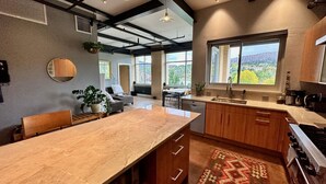 Une cuisine moderne dotée d’un grand îlot central, de meubles en bois et offrant une vue sur l’extérieur.