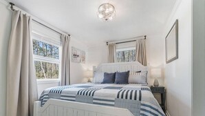Un dormitorio con cama, cortinas, una mesita de noche y una lámpara en el techo.