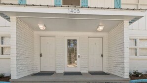 Un edificio con tres puertas blancas, numeradas 1, 2 y 3, y un pequeño ventanal sobre la puerta central.