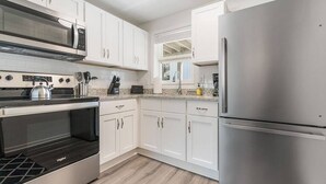 Una cocina moderna con armarios blancos, electrodomésticos de acero inoxidable y encimera de granito.