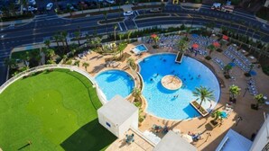 Ein großzügiger Außenpoolbereich mit mehreren Pools, umgeben von Liegestühlen und Palmen.