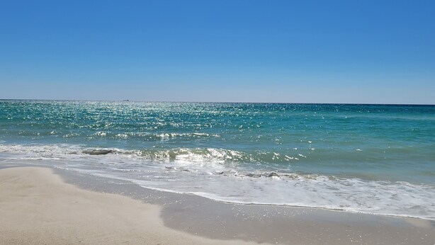 Ein Strand mit klarem, blauen Wasser und einem Sandufer.