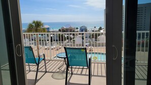 Ein Balkon mit Blick auf das Meer und den Strand, ausgestattet mit zwei Stühlen und einem kleinen Tisch.