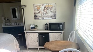 Ein gemütliches Schlafzimmer mit Bett, kleinem Schreibtisch, Stuhl und Küchenzeile.