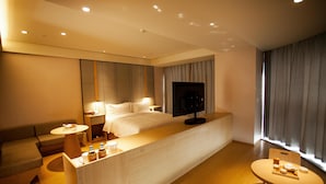 A modern hotel room with a bed, a TV, a desk, a sofa, and a small table with toiletries. - Ji Hotel (Suzhou)