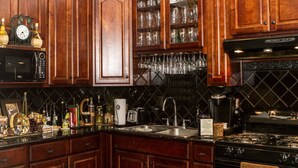 A kitchen with wooden cabinets, a black microwave, a gas stove, and a sink. - La Villa By The Rivewalk Gardens & Pavilions (San Antonio)