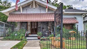 A building with a covered entrance, two flags, and a signboard. - La Villa By The Rivewalk Gardens & Pavilions (San Antonio)