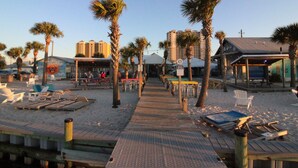 Een pad aan het strand met palmbomen, strandstoelen en tafels.