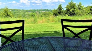 A view from a table with two chairs, overlooking a grassy field with trees and a distant tower. - Newly remodeled condo minutes to the Strip, Lake & SDC with AMAZING views! (Branson)
