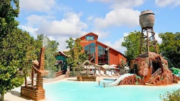 A resort with a swimming pool, a water feature, and a building with a sign. - Newly remodeled condo minutes to the Strip, Lake & SDC with AMAZING views! (Branson)