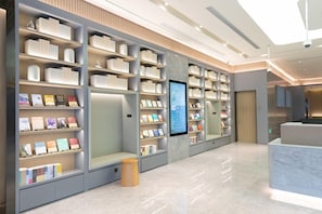 A modern library with bookshelves, a digital display, and a marble reception area.