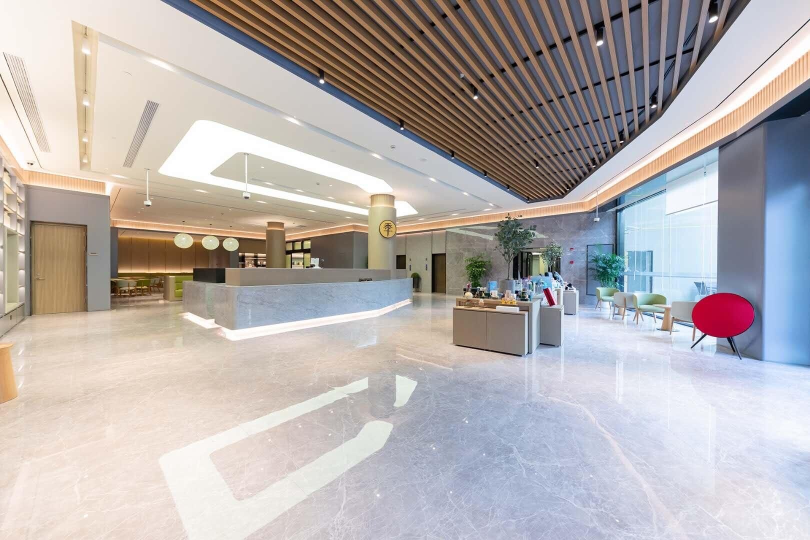 A modern lobby with a reception desk, seating area, and large windows.