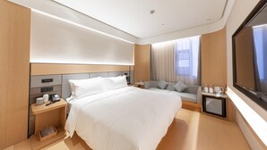 Una habitación de hotel con una cama grande, mesitas de noche, televisor y ventana con cortinas.