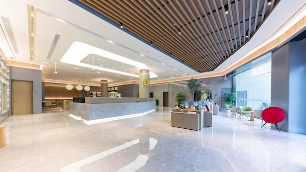 Un moderno hall de entrada con mostrador de recepción, zona de estar y ventanas amplias.