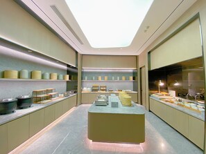 A modern kitchen with a central island, shelves with containers, and a skylight.