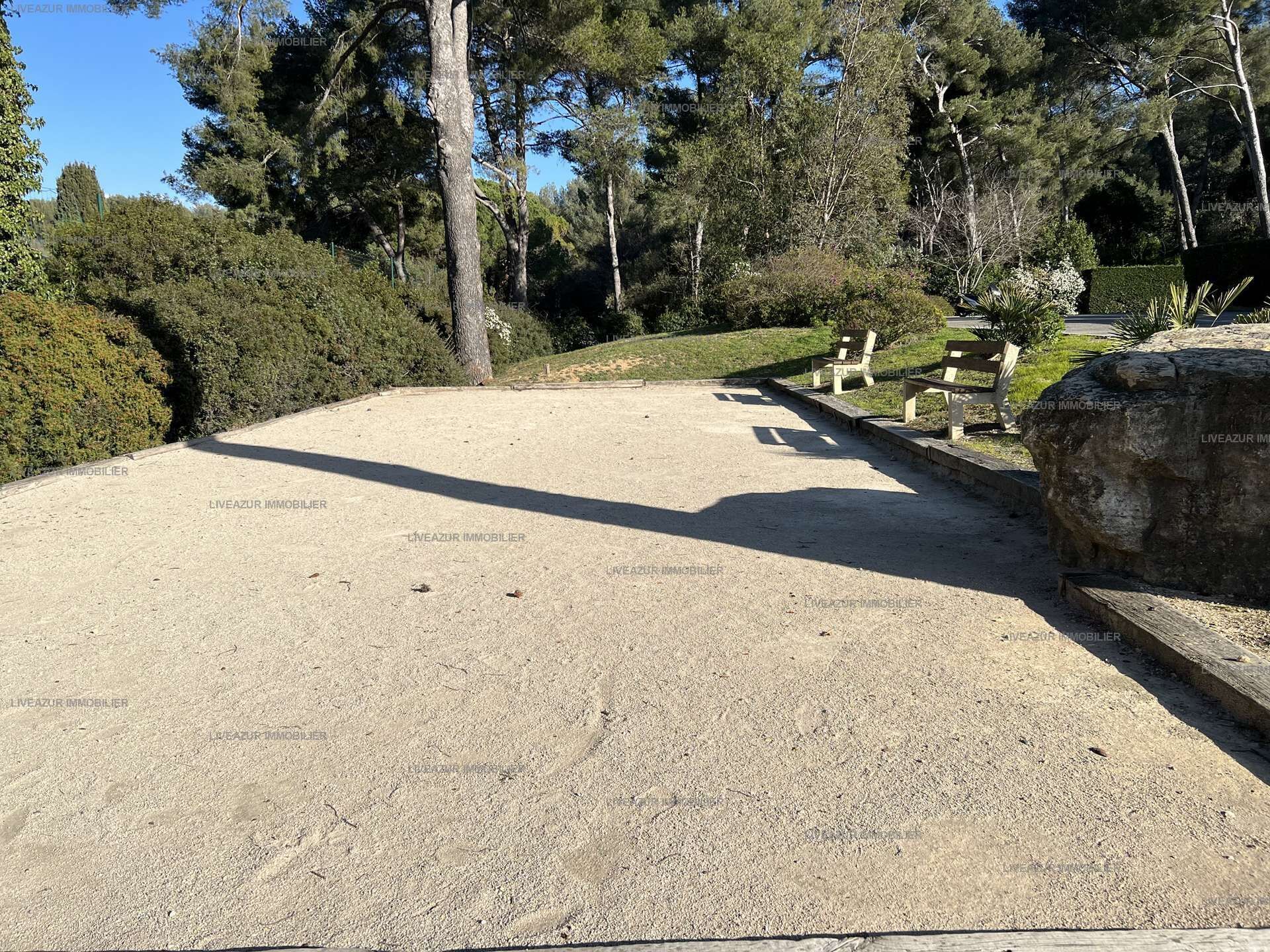 A gravel parking area with benches and a large rock.