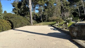 Ein Kiesparkplatz mit Bänken und einem großen Felsen, umgeben von Bäumen.